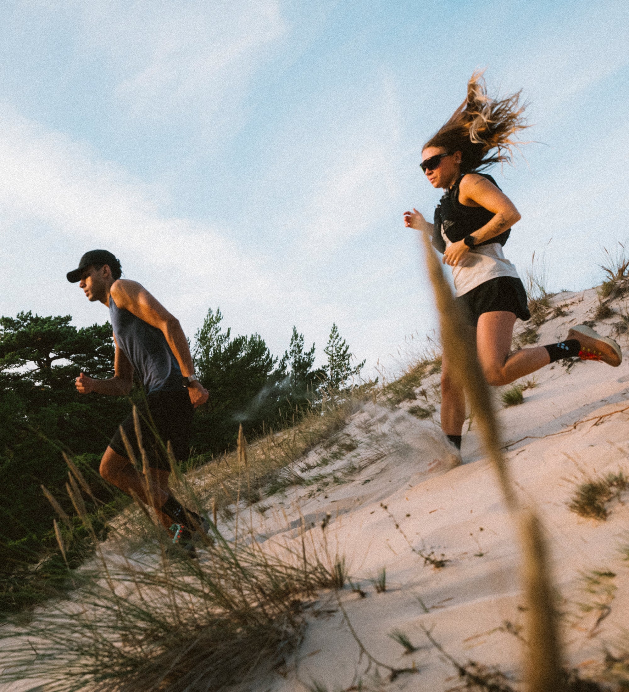 Man and woman running down sand dunes