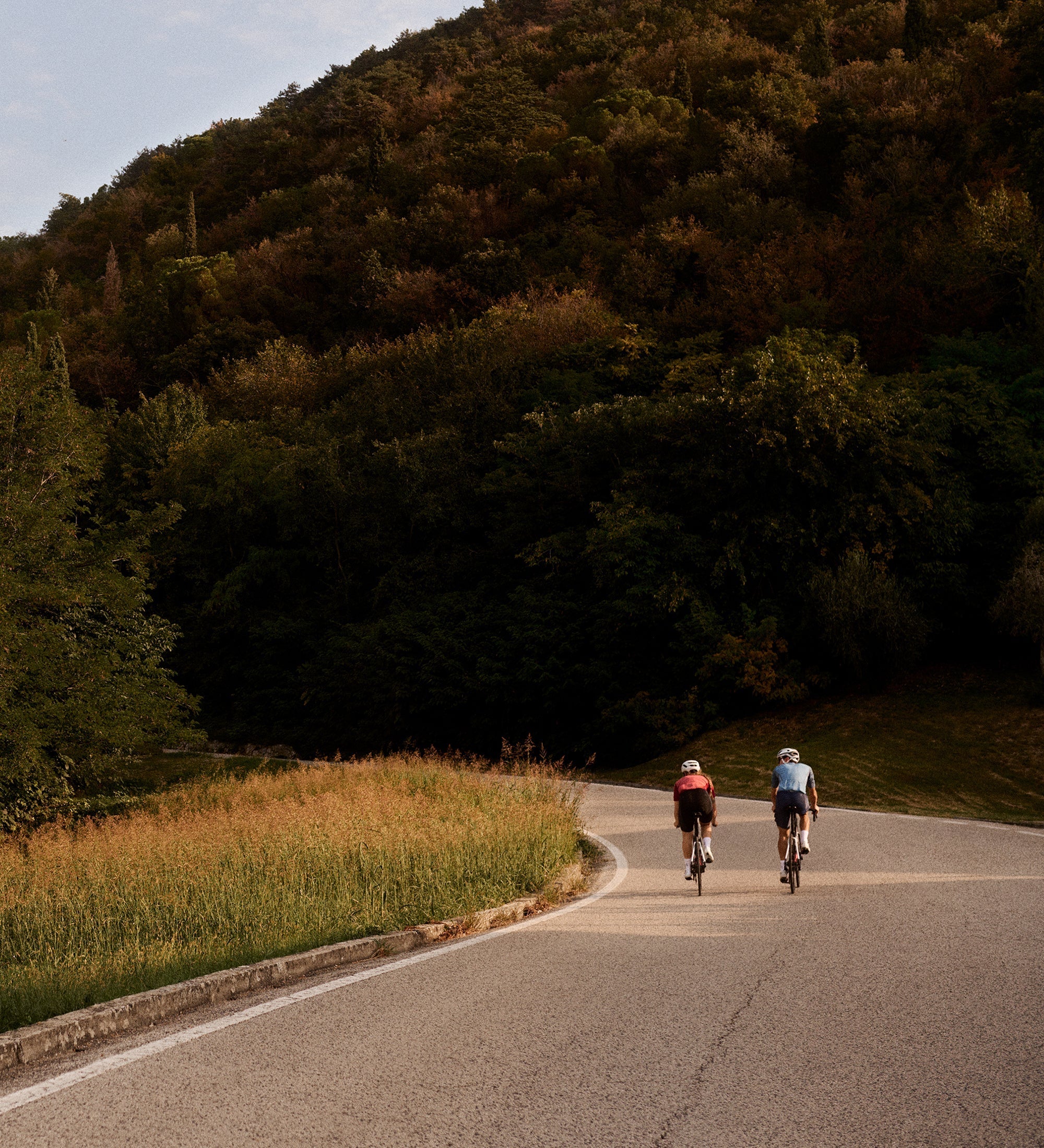 Deux personnes faisant du vélo sur la route au pied d'une grande colline