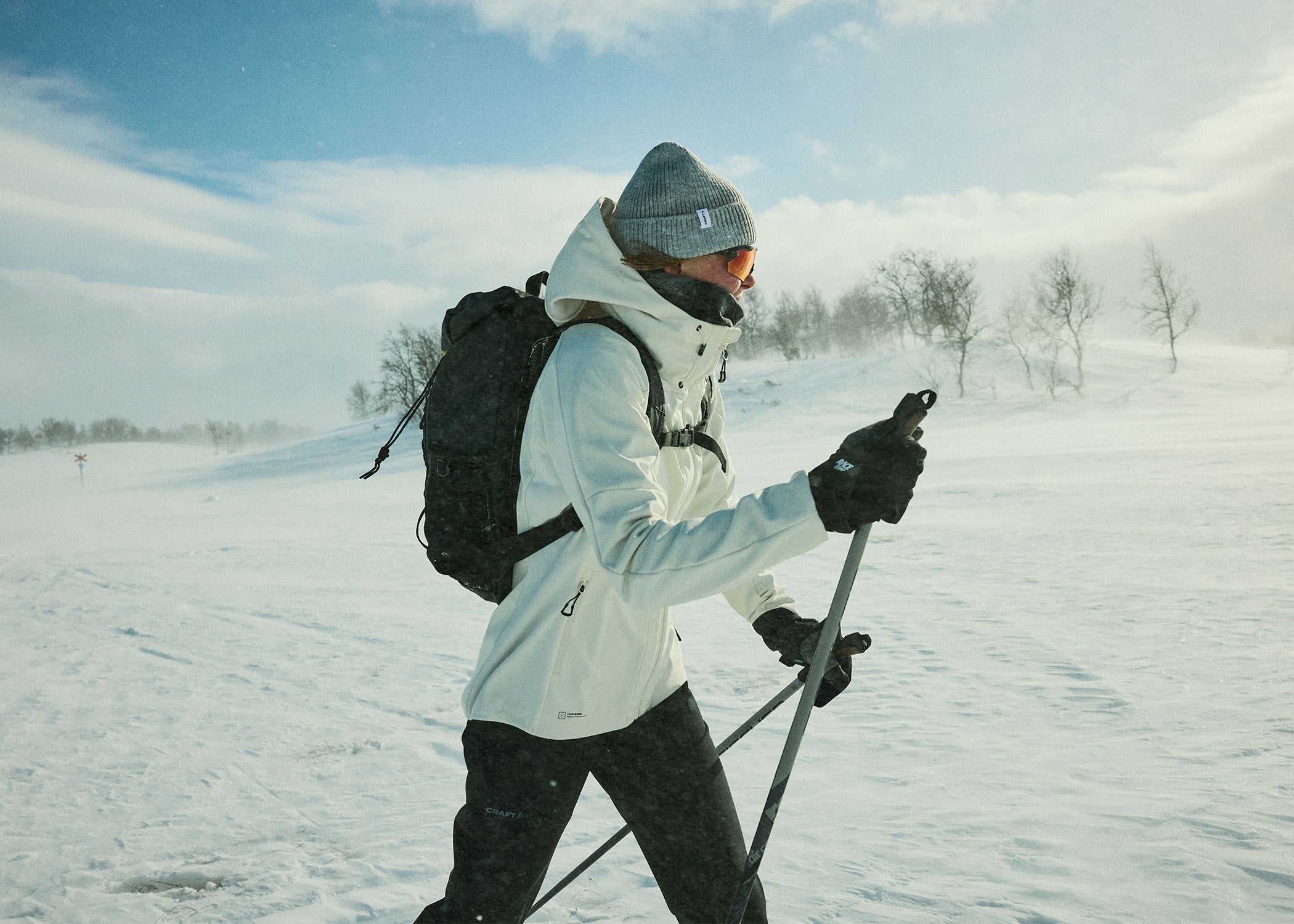 Personne skiant dans un paysage enneigé avec un sac à dos et des bâtons de ski.