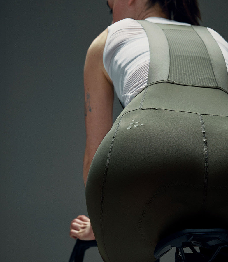 Person wearing green overalls with a gray background