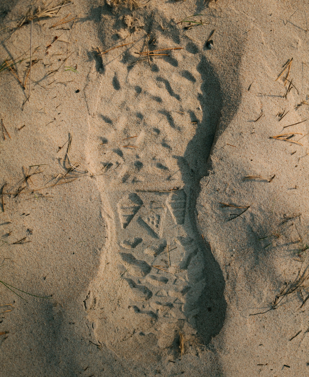 Footprint in sand with a brand logo
