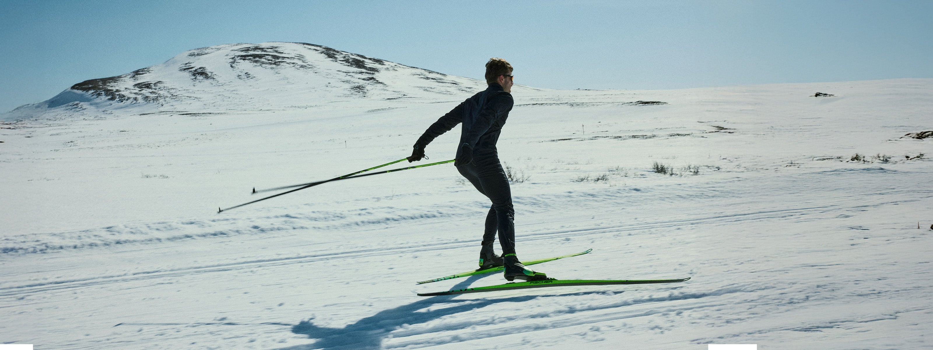Person cross-country skiing on a snowy landscape with mountains in the background