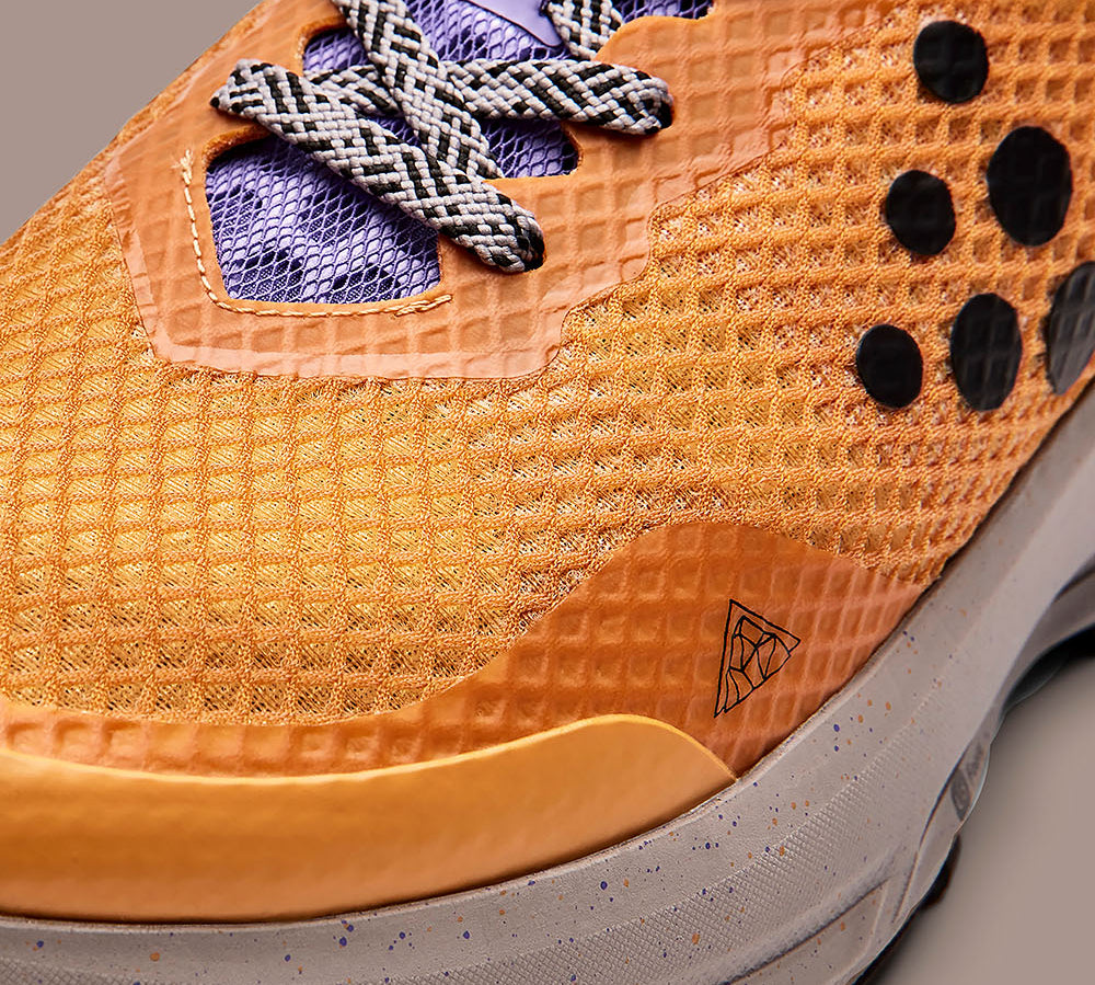 Gros plan sur une chaussure de sport orange avec une semelle texturée et le logo de la marque.