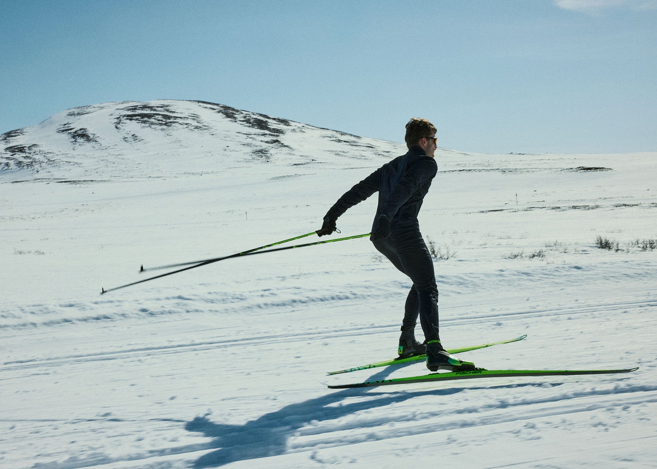 Personne pratiquant le ski de fond dans un paysage enneigé avec des montagnes en arrière-plan