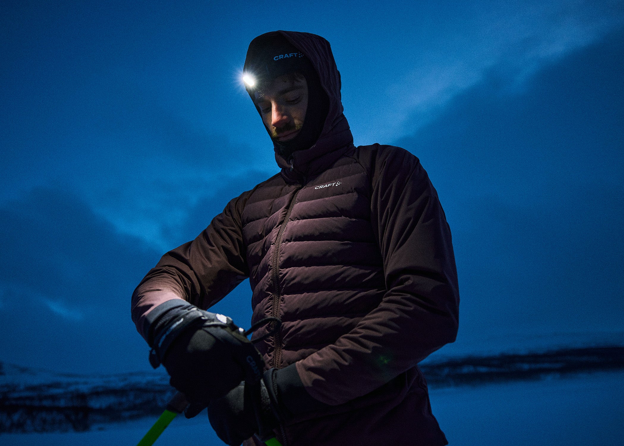 Personne vêtue d'une veste sombre et équipée d'une lampe frontale, sur fond de ciel bleu