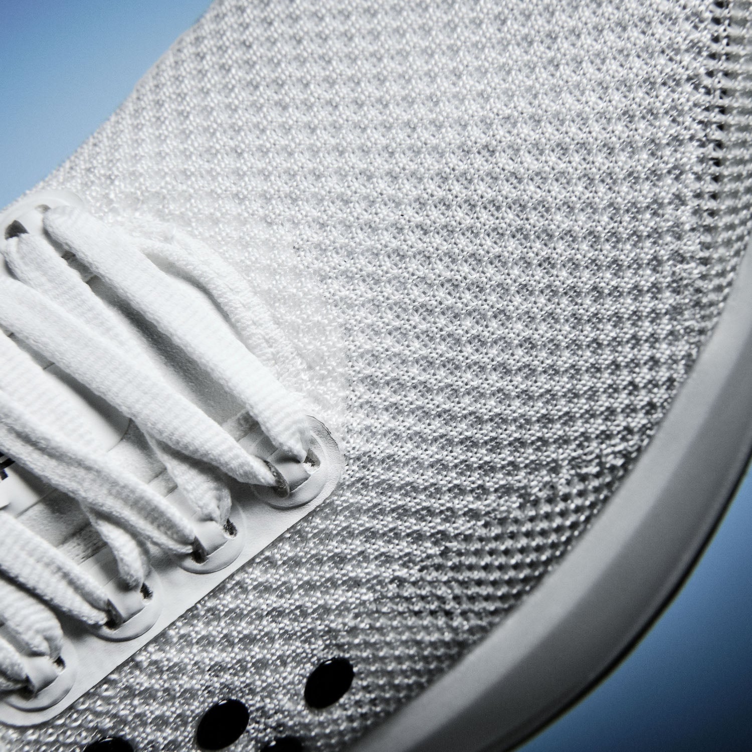 Gros plan sur une semelle de chaussure texturée avec des lacets blancs sur fond bleu