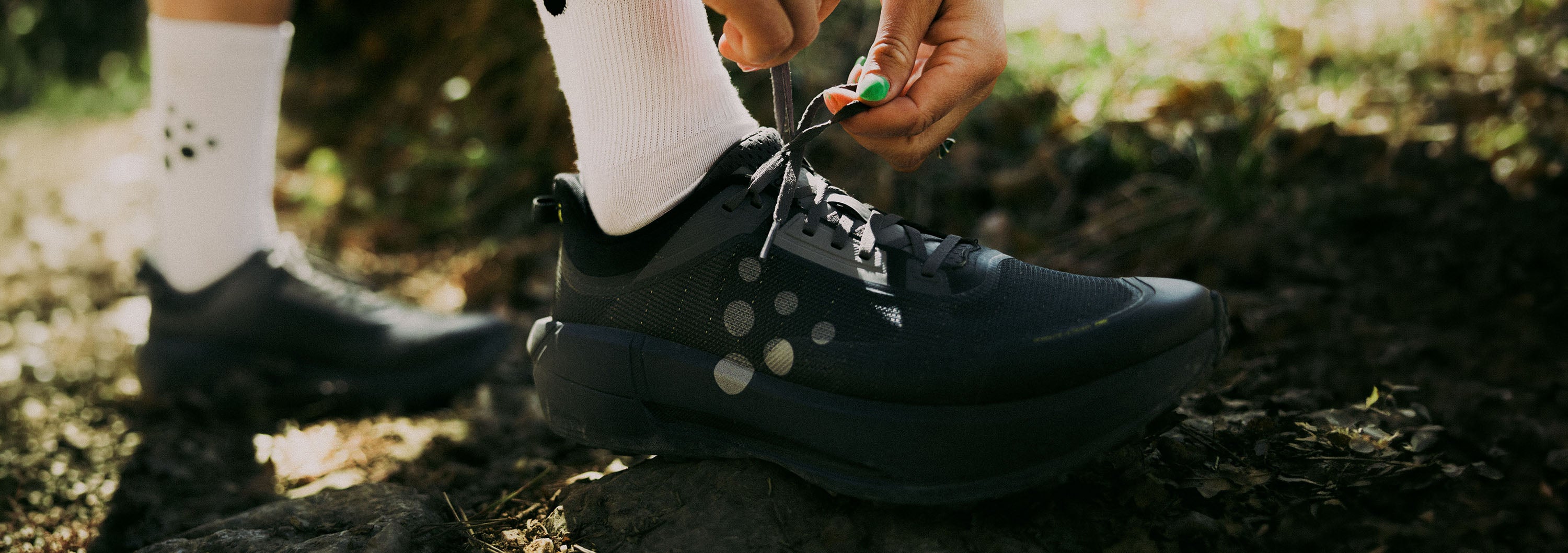 Person tying shoelaces on black shoes outdoors