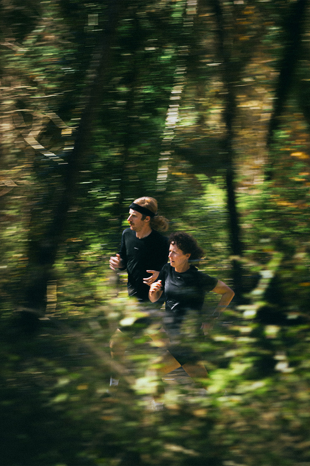 Two people running through a forest with a blurred effect