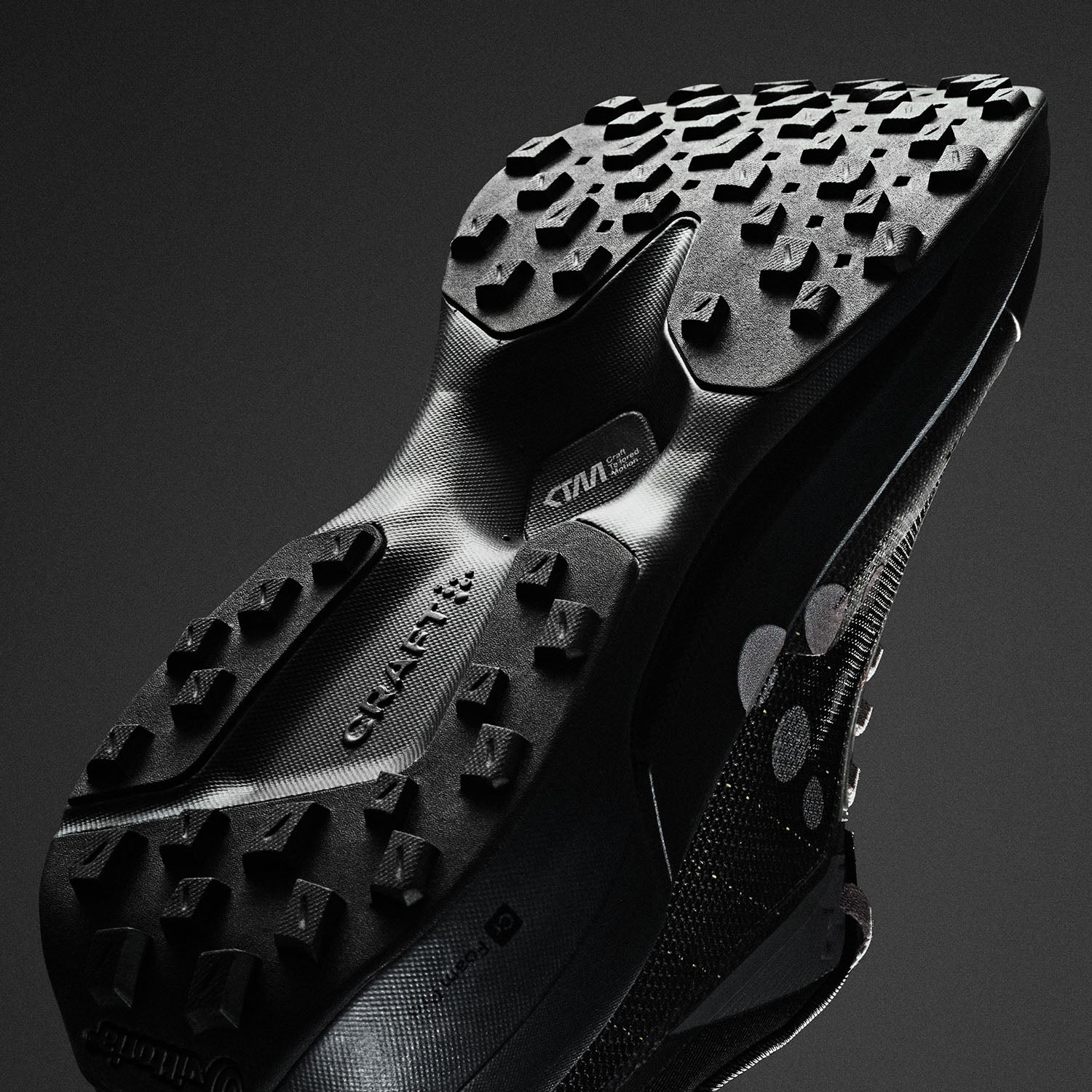 Close-up of a black athletic shoe sole with brand logos on a dark background