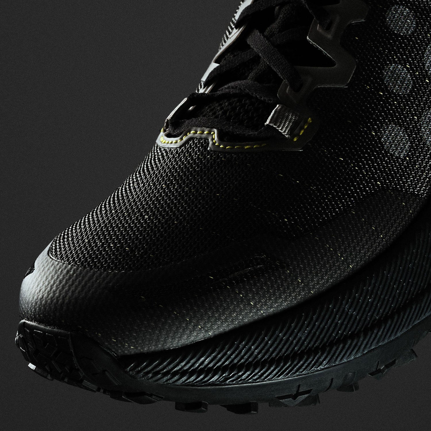 Black sneaker with brand logo on a black background