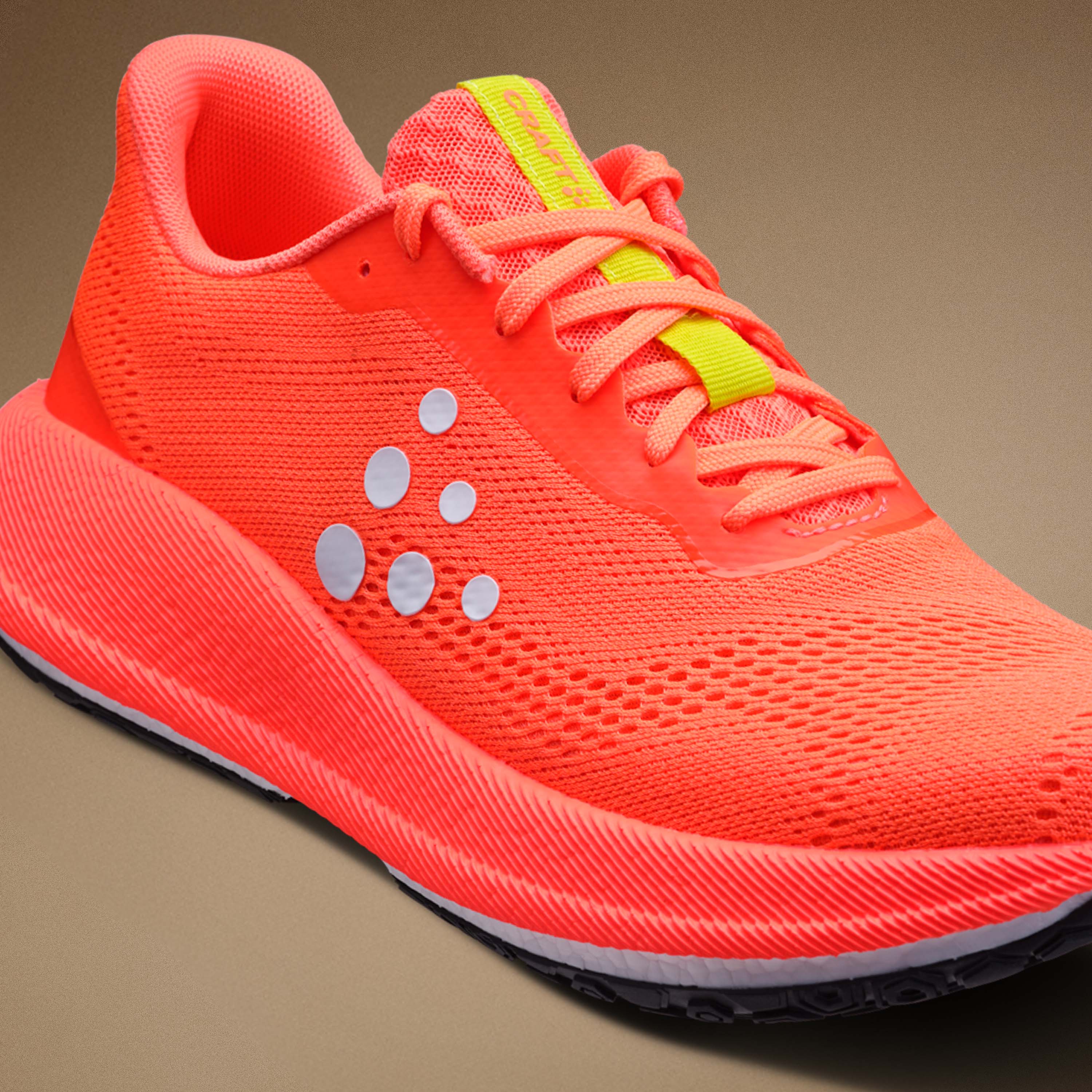 Bright orange running shoe with white accents on a brown background