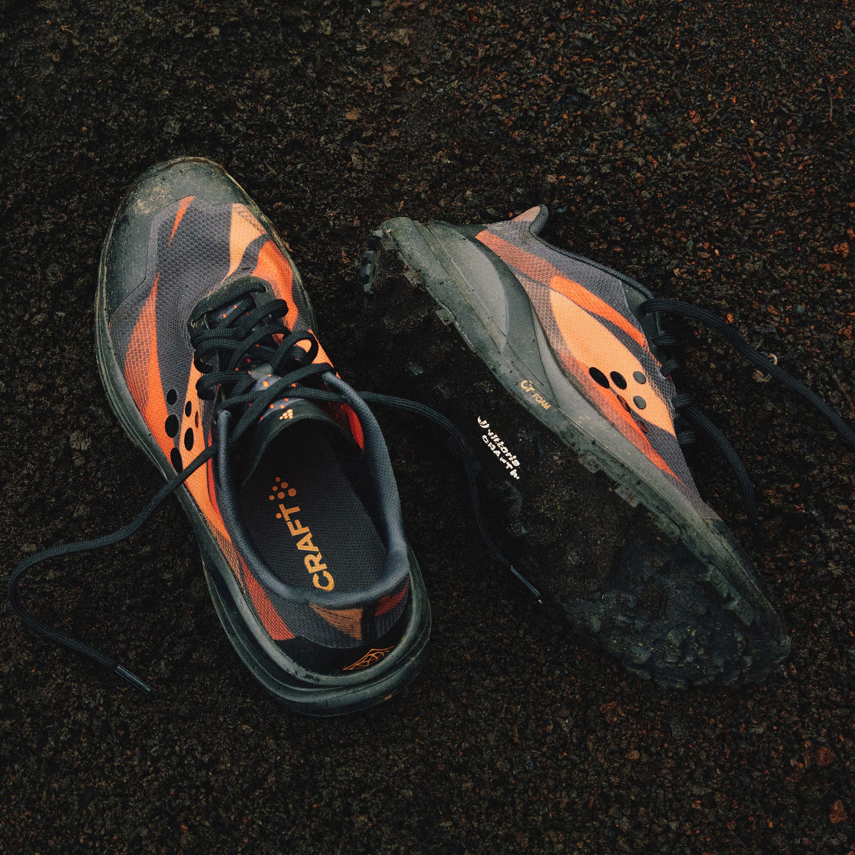 Pair of orange and gray running shoes on a dark surface