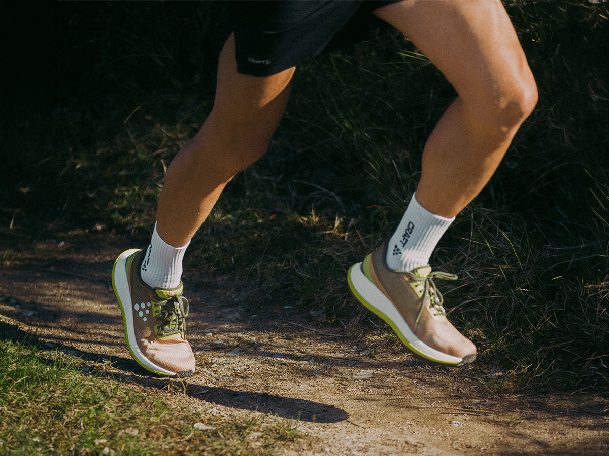 Person running on a trail wearing running shoes and socks.