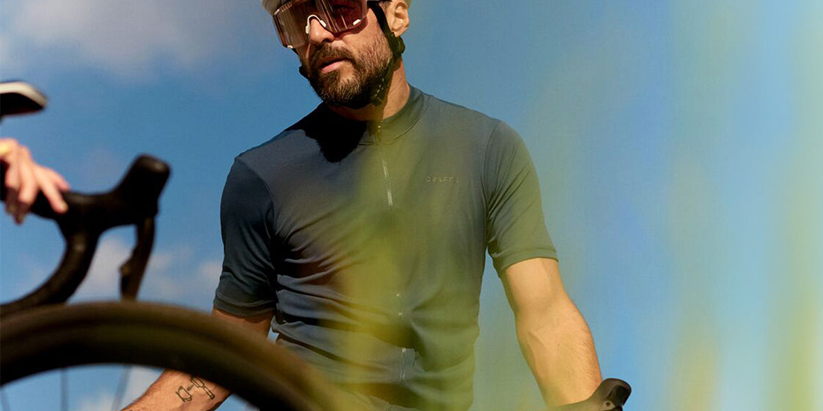 Man on a bicycle wearing a helmet and sunglasses with a blue sky background