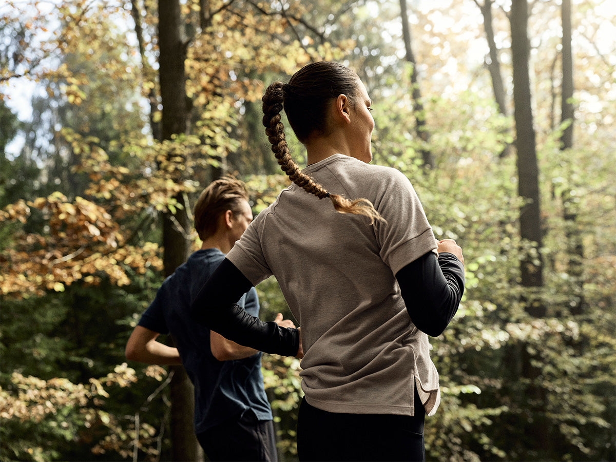 Two people running in a forest on a sunny day