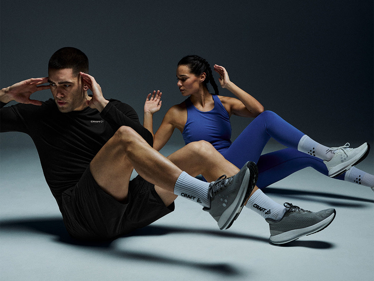 Two people exercising on a gray floor with a dark background