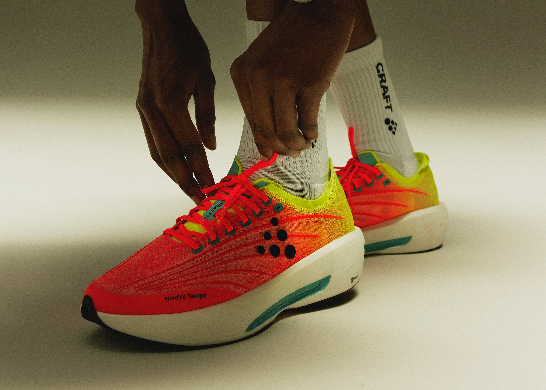 Person reaching down to tie sneakers.