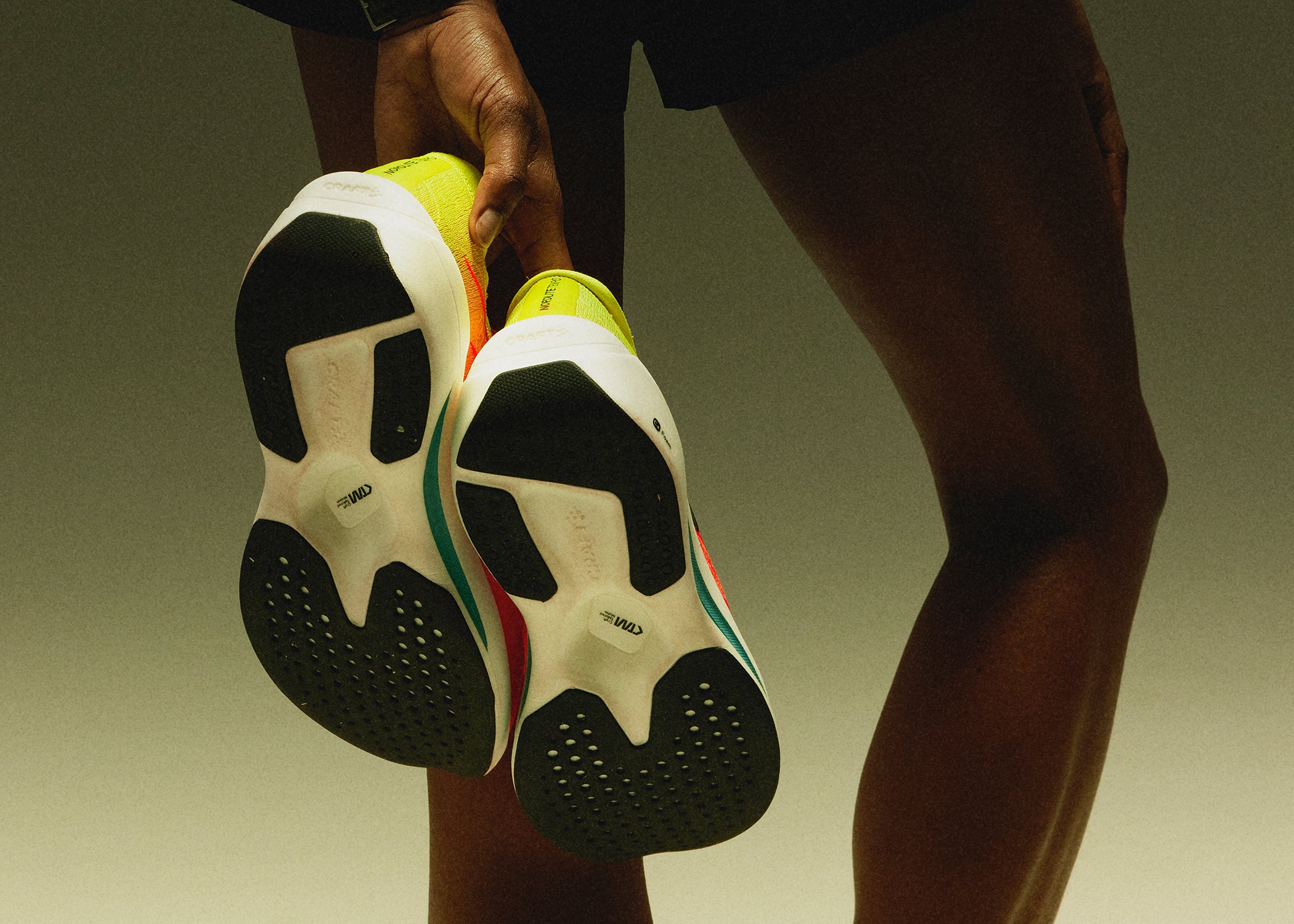 Person holding two sneakers to show detail of bottom of shoe.