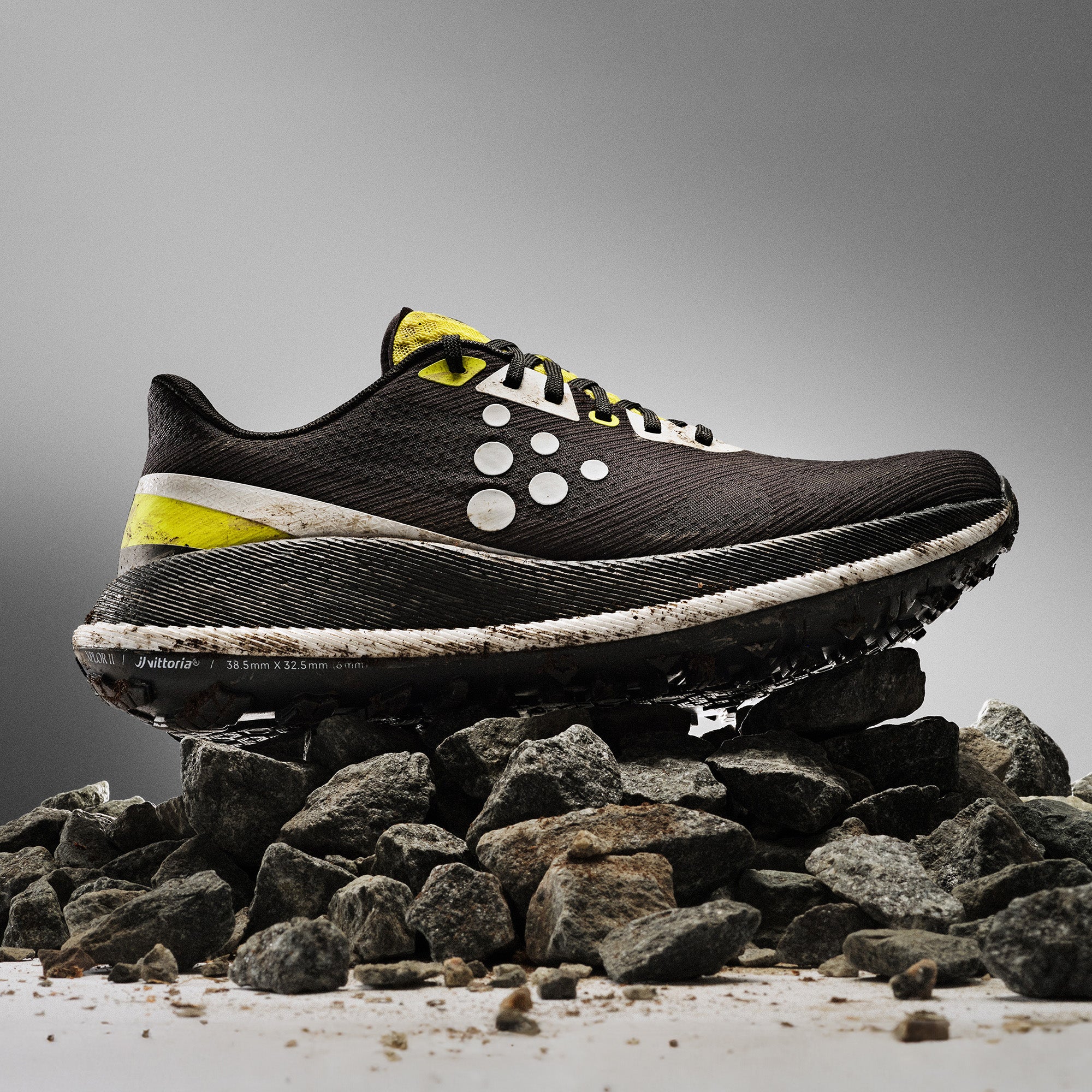 Black and yellow running shoe on a pile of rocks with a gray background