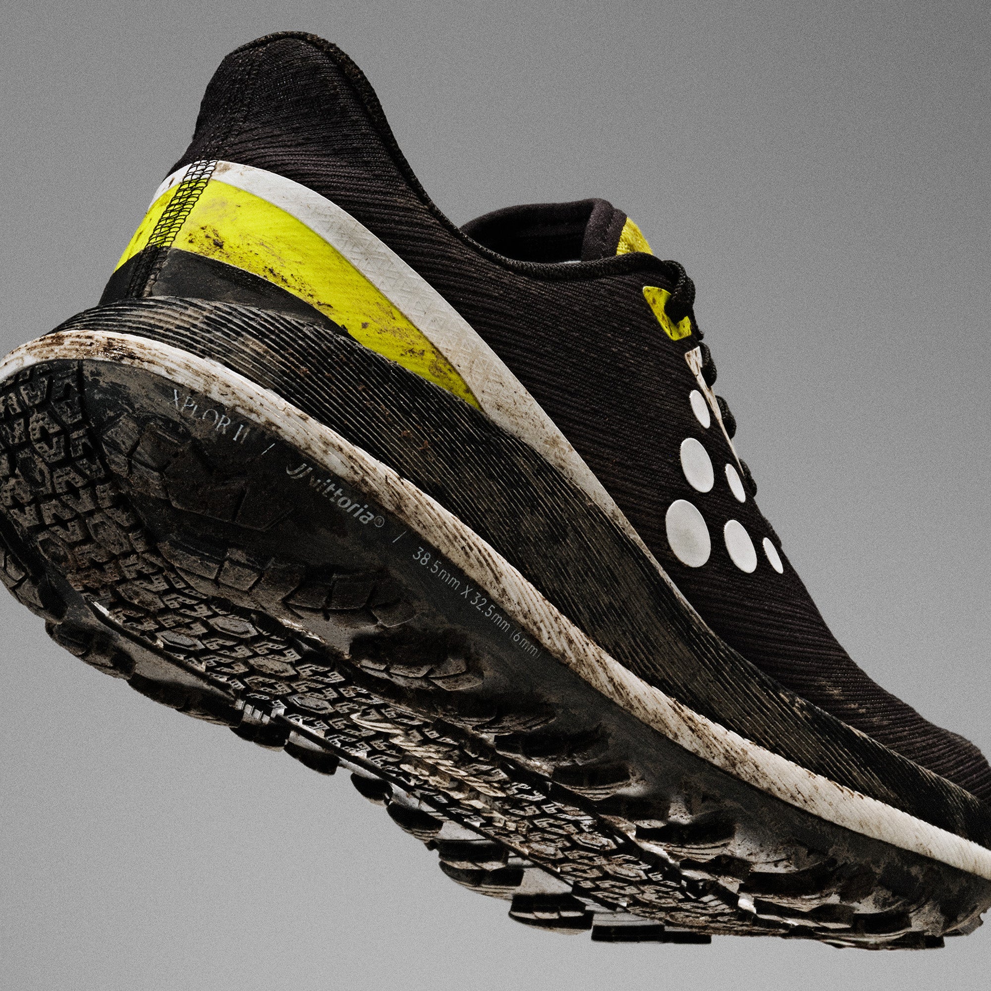 Black running shoe with yellow accents on a gray background