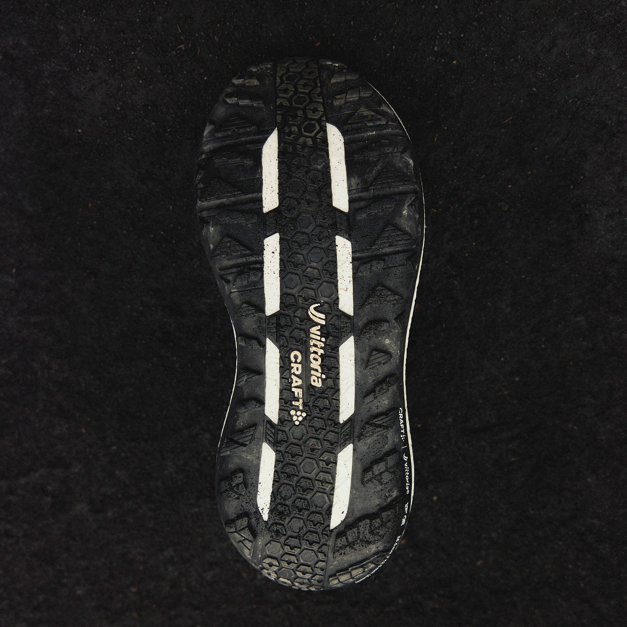 Close-up of a black and white sole with a brand logo on a black background